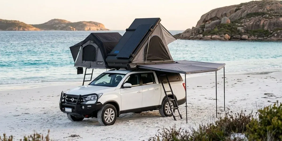 A 4WD camper parked on the white sand of Lucky Bay with turquoise water and granite headlands beyond