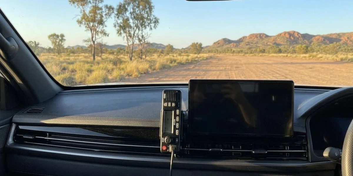 UHF radio mounted on dashboard of a 4WD vehicle driving through remote Western Australian outback landscape with no buildings or infrastructure visible